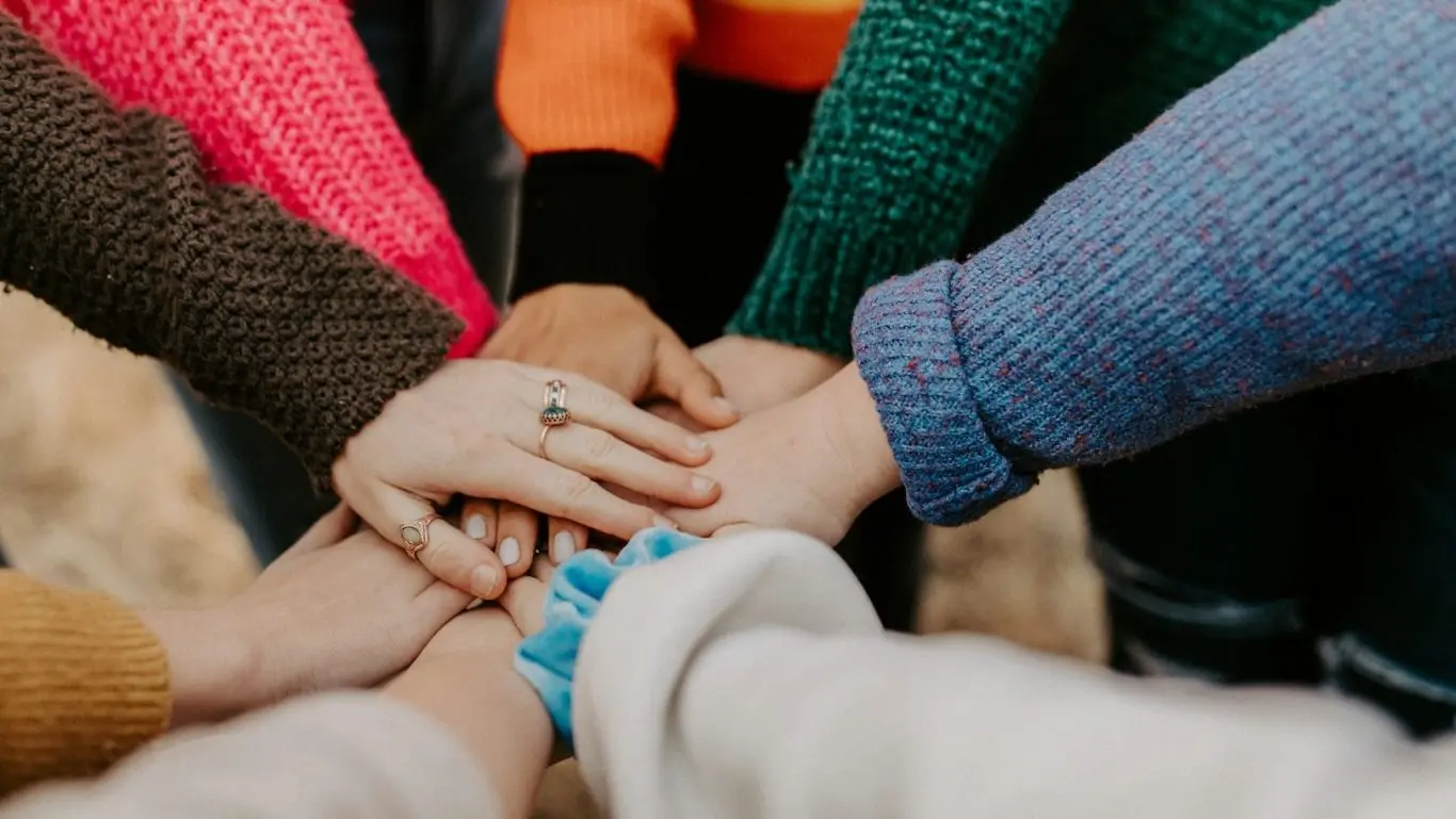 Menschen legen ihre Hände gemeinsam in die Mitte